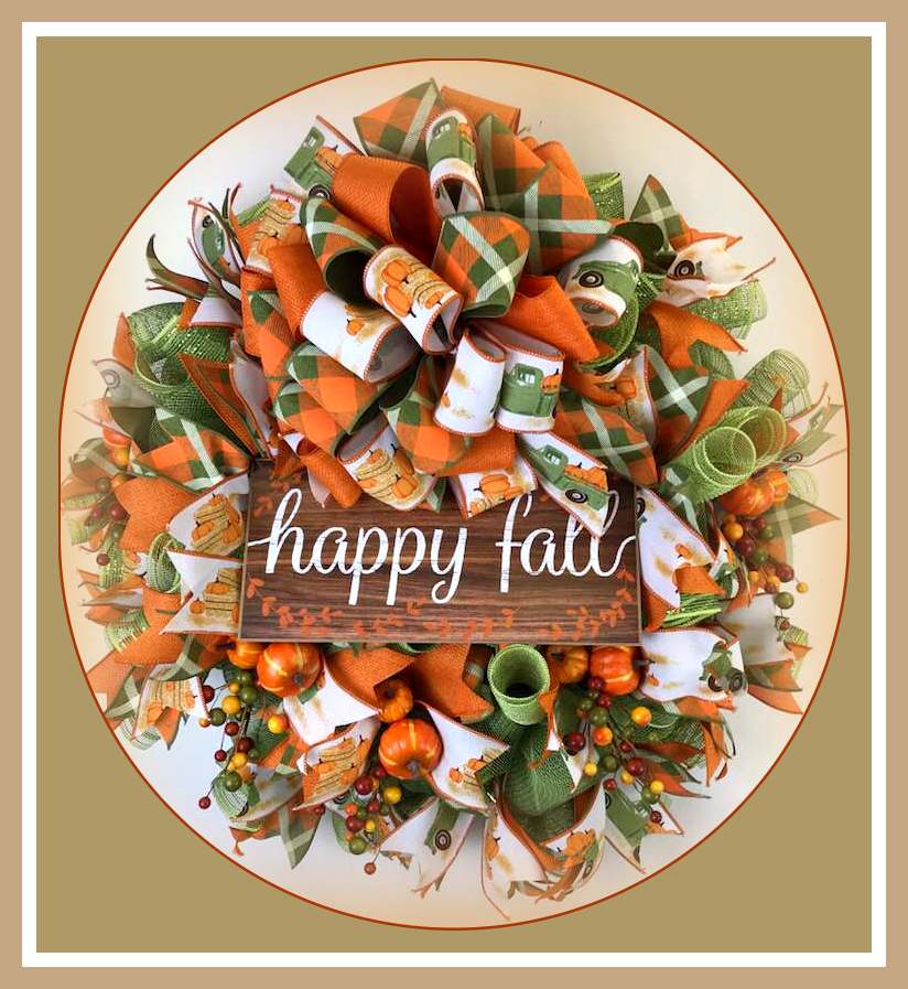A wreath adorned with multiple print ribbons and a 'happy fall' sign