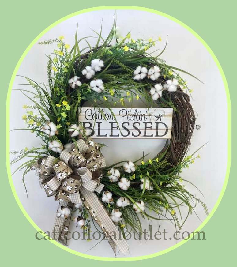 a grapevine wreath featuring faux greenery, cotton, tiny yellow flowers, printed ribbon and a 