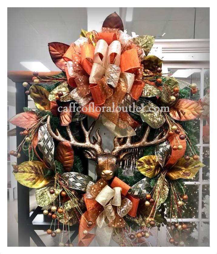A Christmas wreath adorned with metallic magnolia leaves, glitter berries, a multicolored bow and a deer head