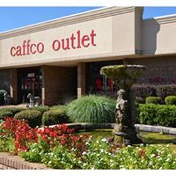 A cherubic fountain and colorful florals outside the entrance to the Caffco Outlet storefront