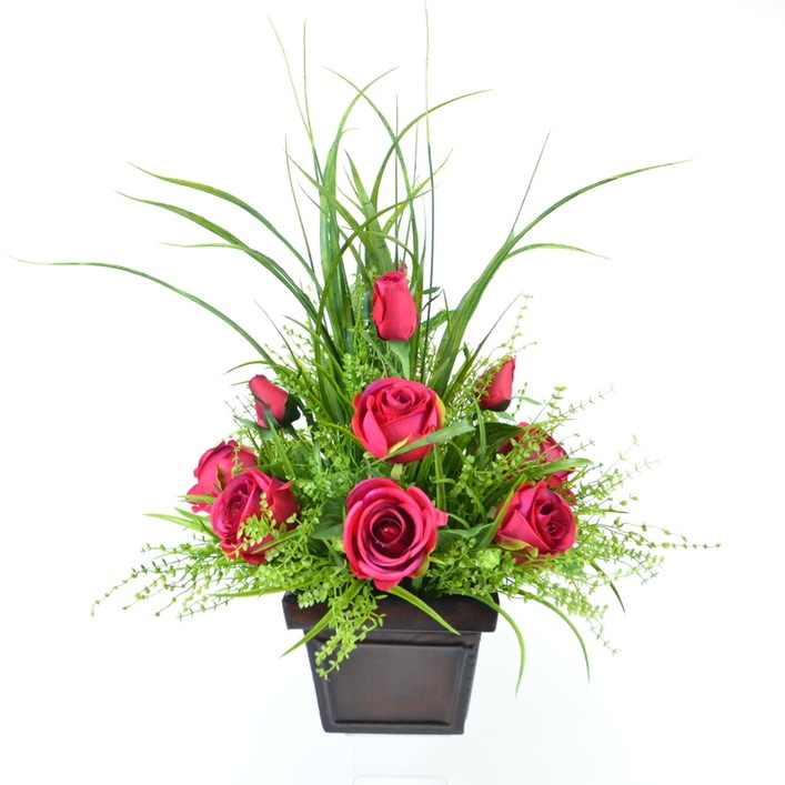 A floral arrangement of faux roses and greenery in a metal container